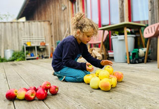 Kind spielt mit Äpfeln